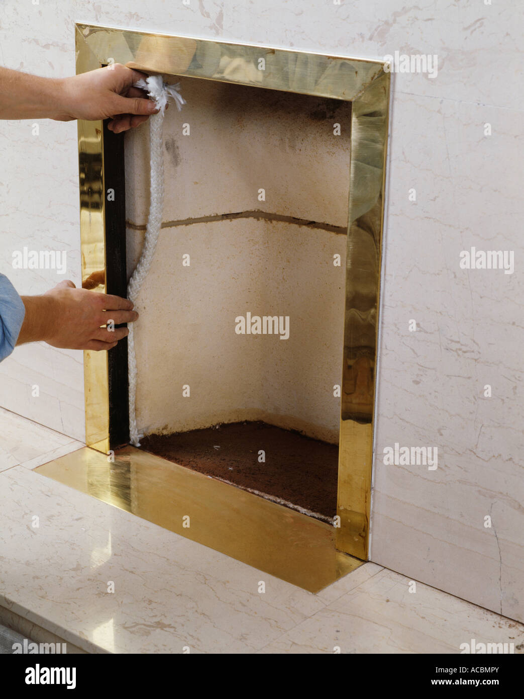 Close up di mani di montaggio telaio in ottone nel camino Foto Stock