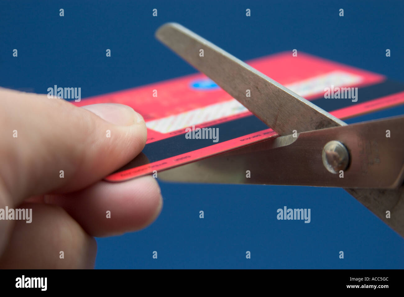 La mano di presa di un paio di forbici il taglio di una carta di credito Foto Stock