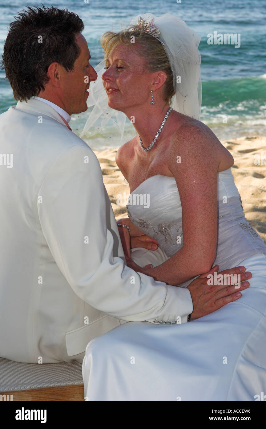 Sposa e lo sposo seduto sulla calda spiaggia di sabbia dorata nel tardo pomeriggio Foto Stock