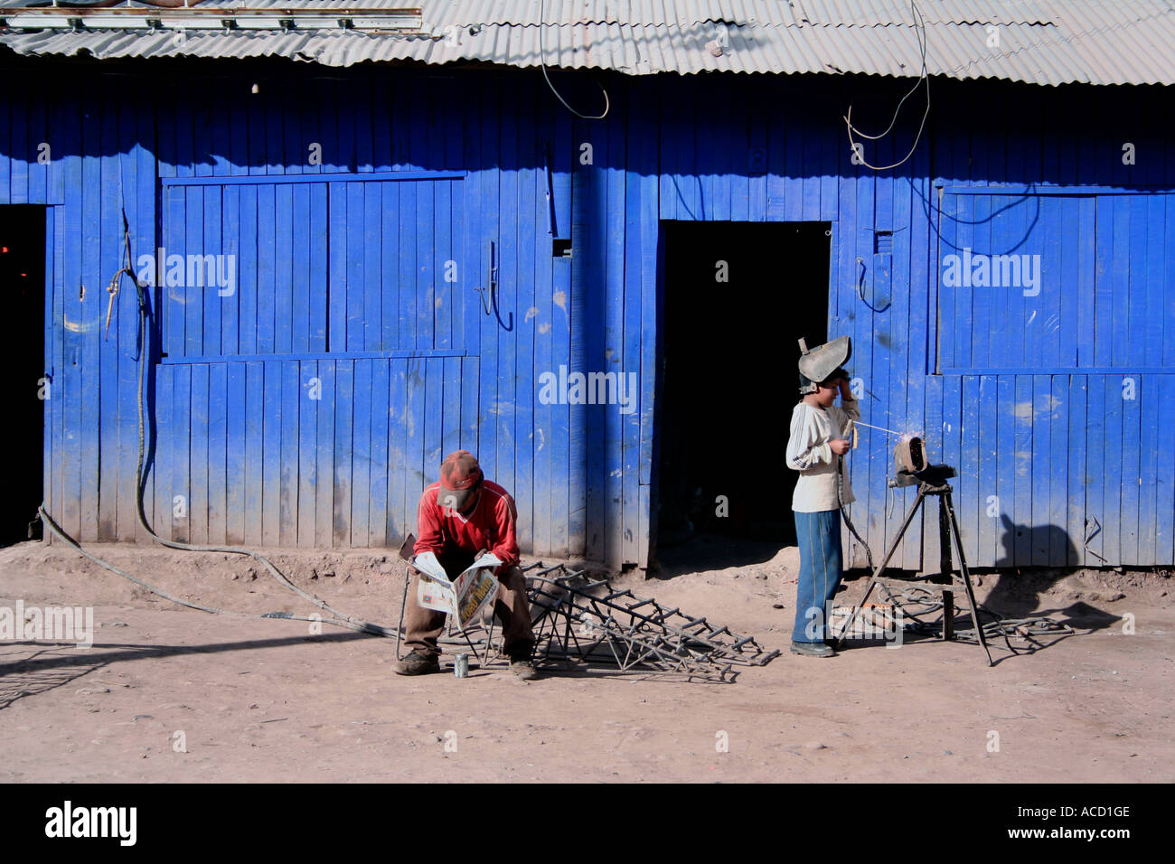 Ragazzo al di fuori di saldatura officina blu, Cuzco, Perù Foto Stock