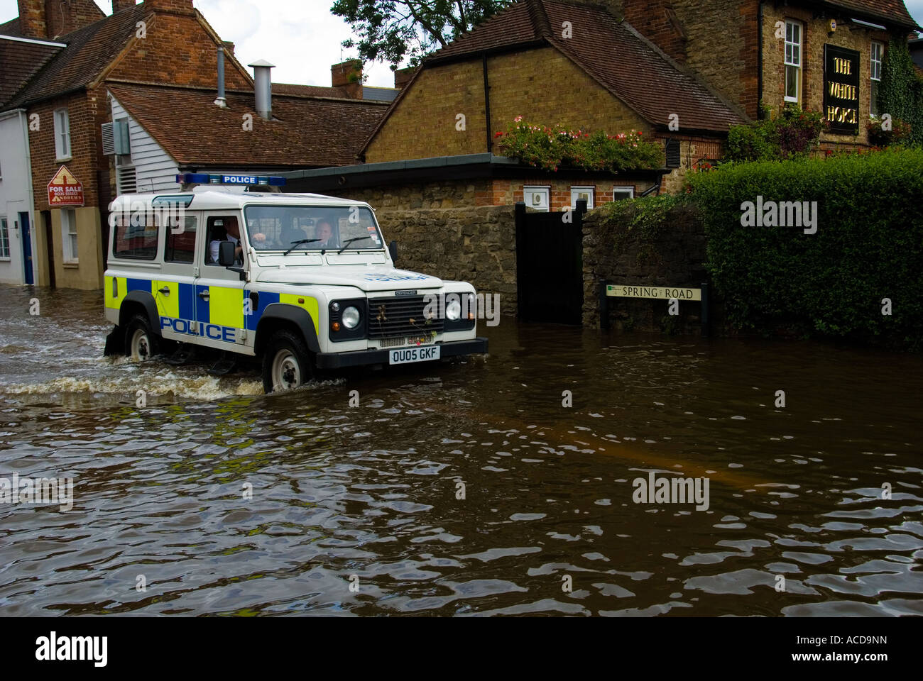 Una polizia Land Rover guidando lungo una strada allagata Foto Stock