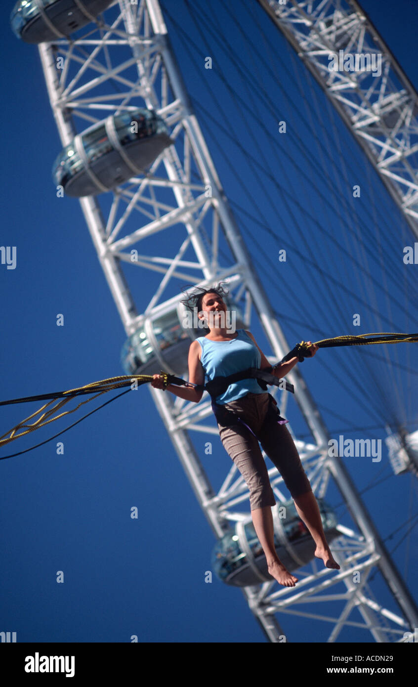 Giovane donna bungee jumping su un trampolino prima l'Occhio di Londra, South Bank di Londra, Inghilterra, Gran Bretagna Foto Stock