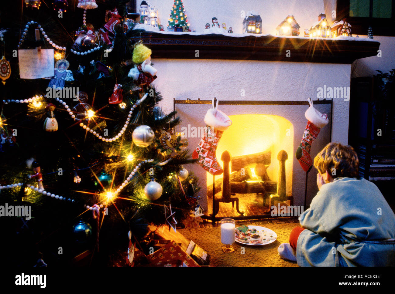 Scena di Natale ragazzo in attesa di Santa a casa caminetto Foto Stock