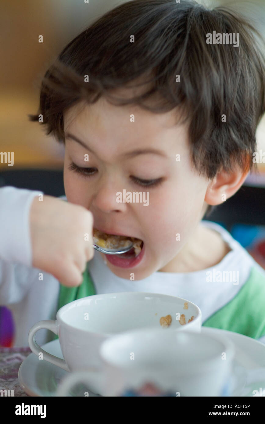 Ragazzo di mangiare un pasto, munches lontano sulla sua cereali per la prima colazione. Modello rilasciato Foto Stock