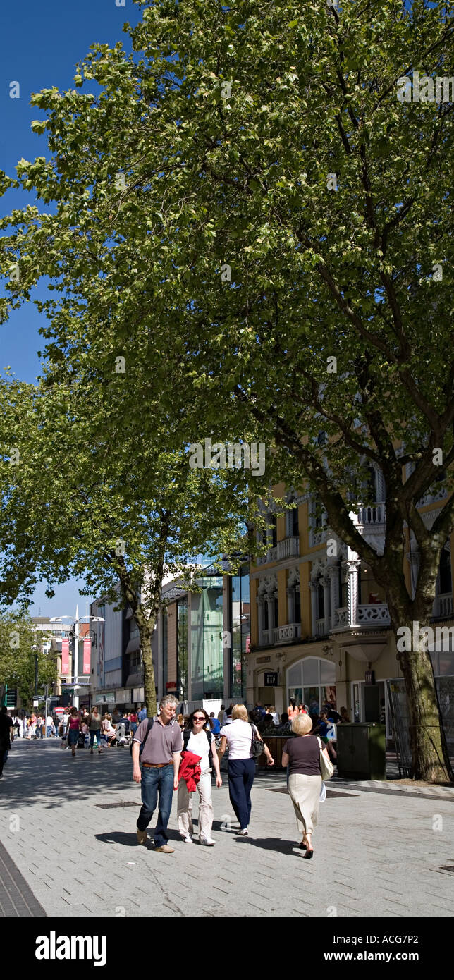 La gente camminare attraverso la parte ombreggiata del centro città strada pedonale dello shopping Cardiff Wales UK Foto Stock