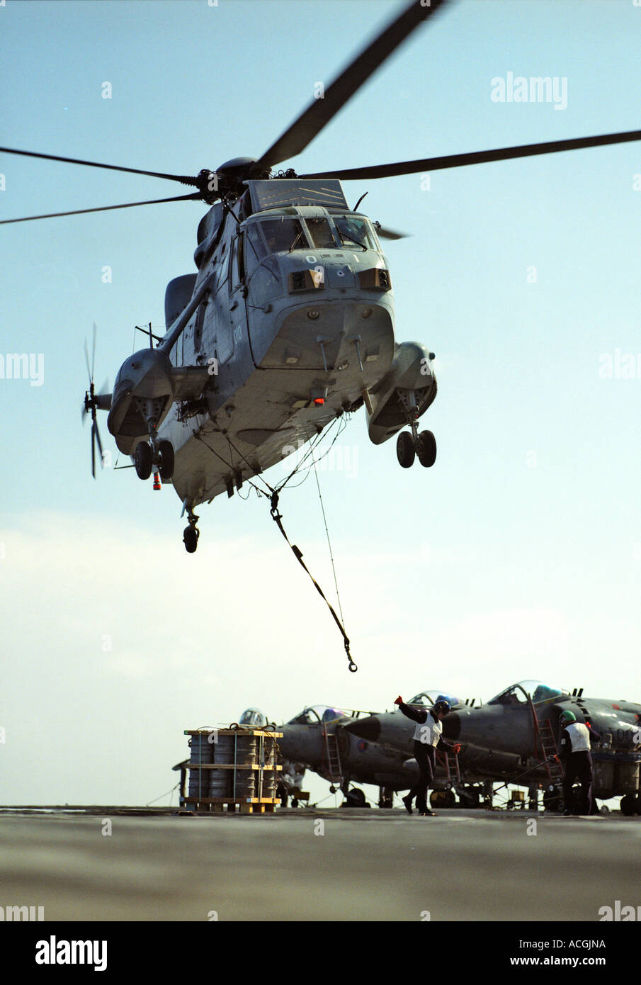 Royal Navy sea king Mark 5 si libra sul ponte di volo HMS Ark Royal di aver consegnato sotto carico imbragati. Vista del pianale Foto Stock