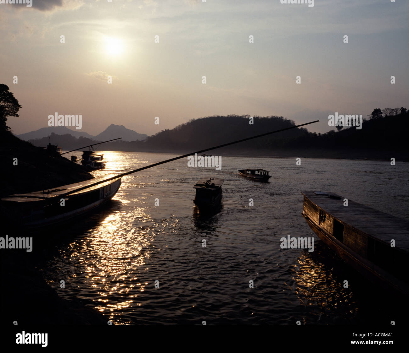 Barche ormeggiate fino al tramonto lungo il fiume Mekong Louang Phabang Laos Foto Stock