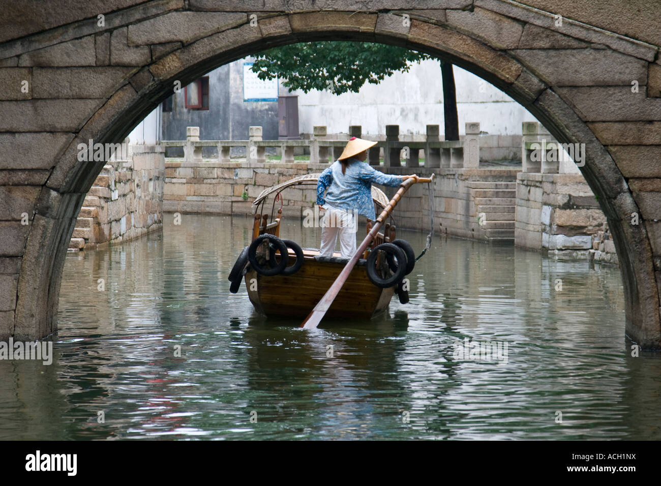 Donna vogatore sotto antico ponte in pietra Tongli Canal Town Cina Foto Stock