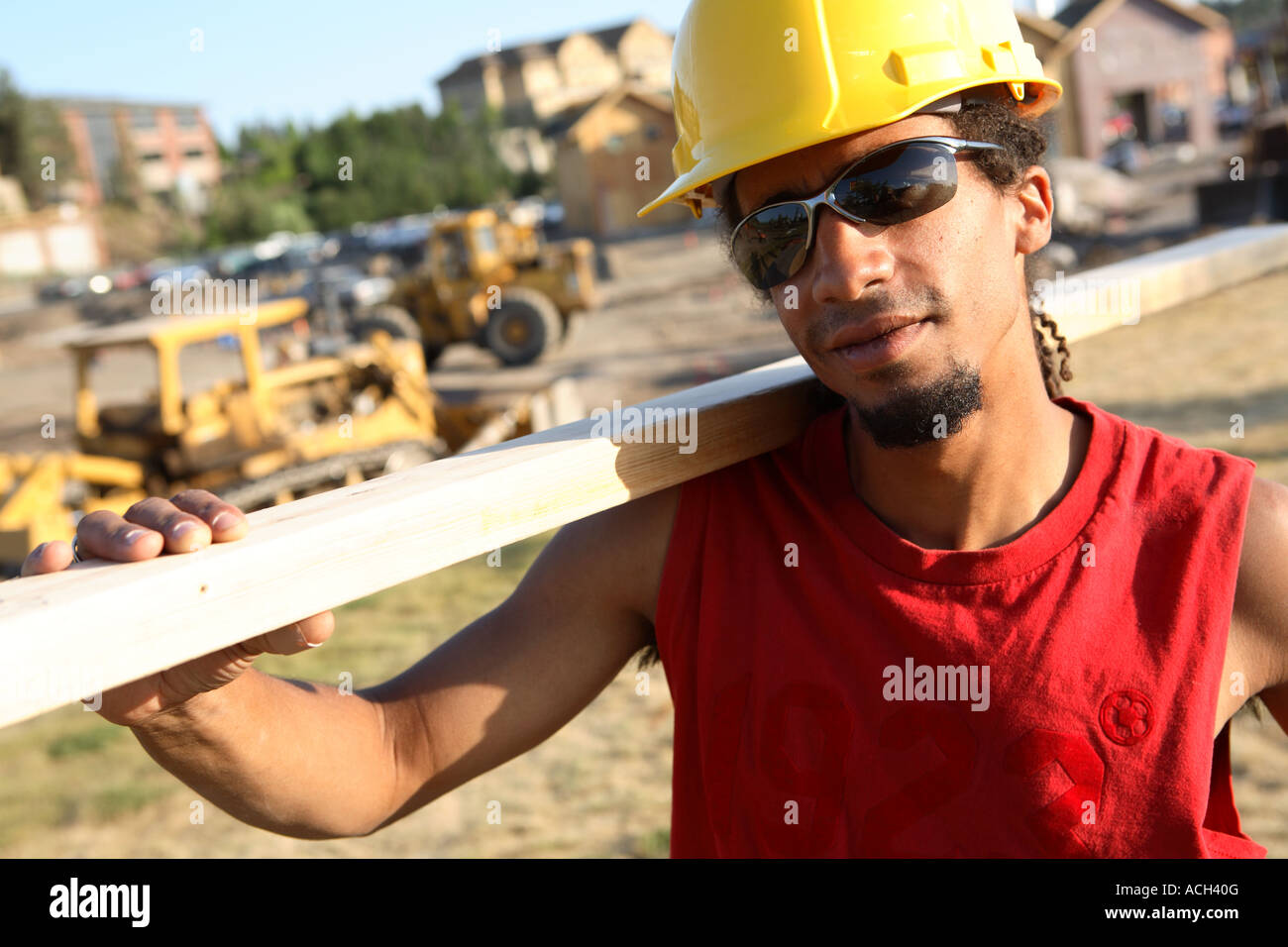 Lavoratore edile con legname sullo spallamento Foto Stock