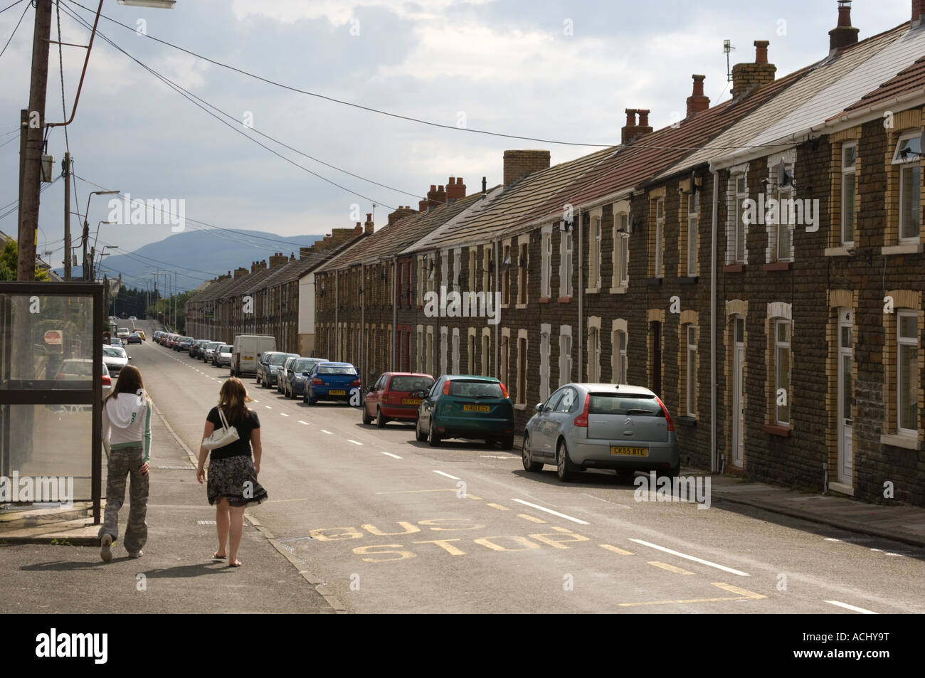 Ex minatori case a schiera sette sorelle Blaendulais Dulais Valley South Wales due ragazze a piedi giù per la strada nella luce del sole Foto Stock