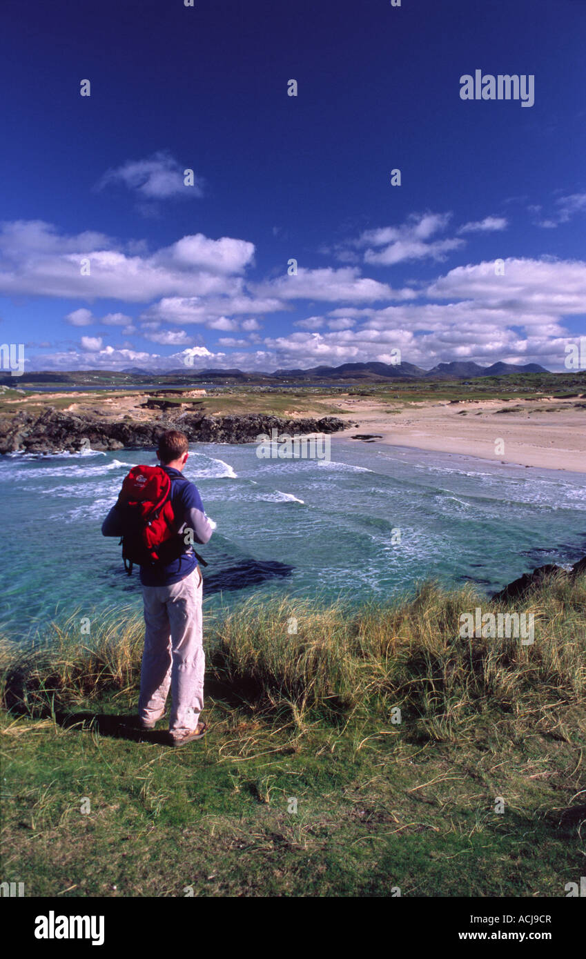 Escursionista cerca su una spiaggia di sabbia sulla riva di Mannin Bay, Connemara, nella contea di Galway, Irlanda. Foto Stock