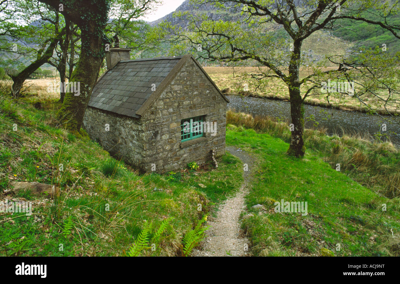 Stalker cottage accanto a un percorso di foresta nel parco nazionale di Glenveagh, County Donegal, Irlanda. Foto Stock