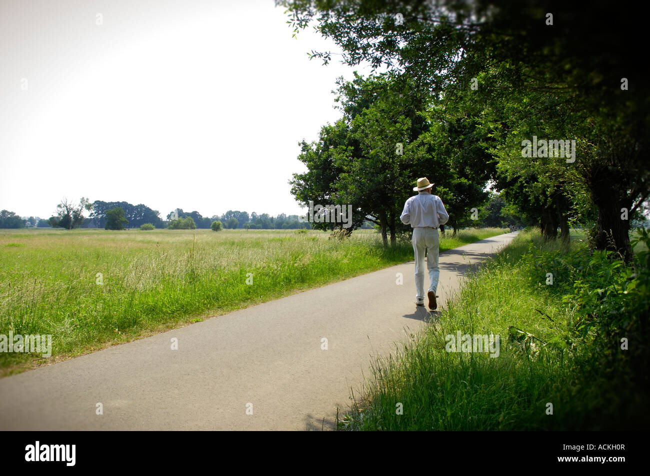 L uomo vestito di bianco gent gentiluomo di mezza età vecchi pensionati a piedi walker passeggiata passeggino paesaggio rurale piacevole riposo idilliaco Foto Stock