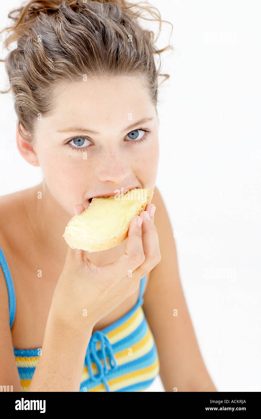 Giovane donna di mangiare una fetta di pane imburrato Foto Stock