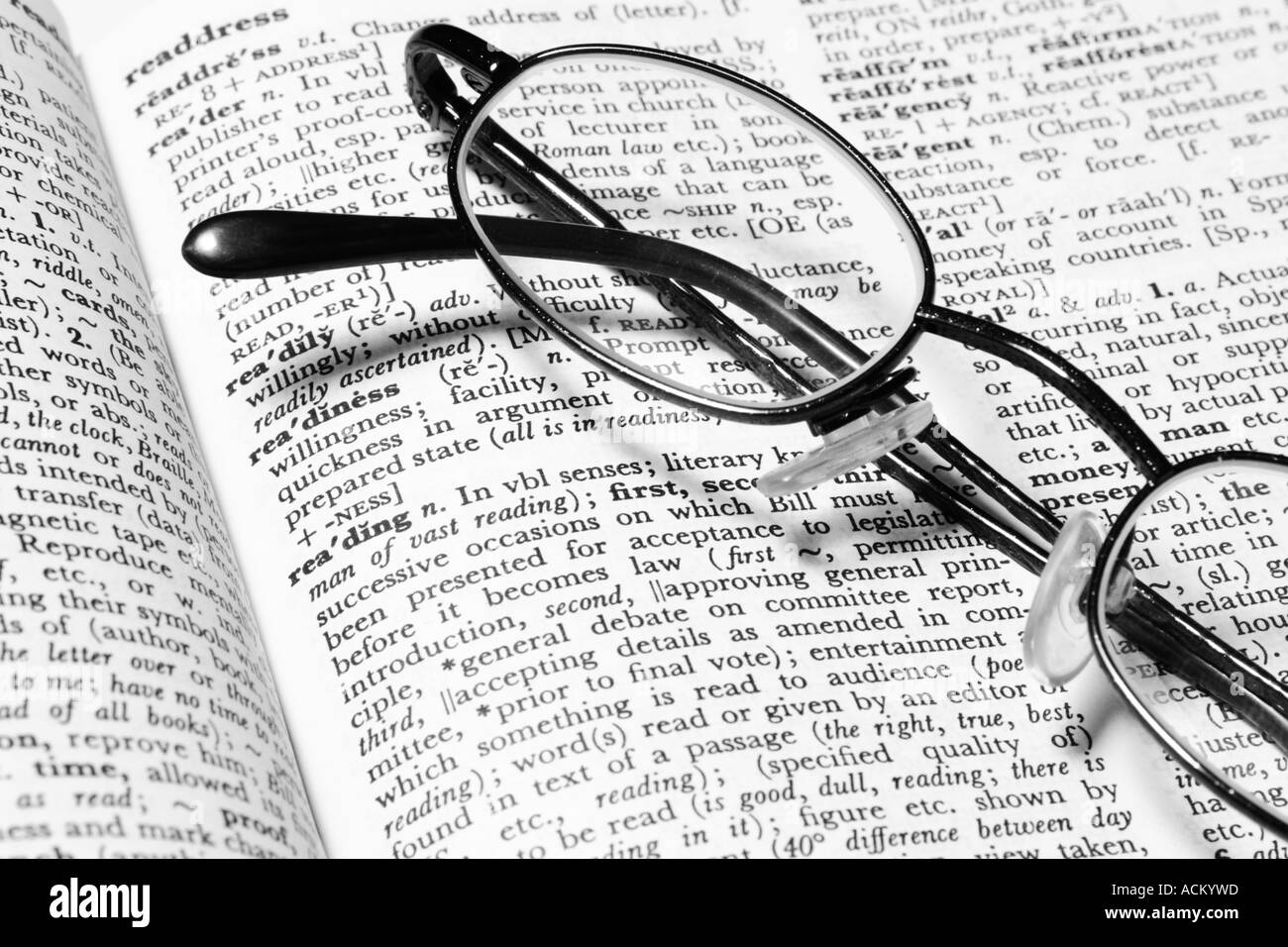 Gli occhiali da lettura in appoggio su un dizionario aperta in corrispondenza della definizione per la lettura della parola Foto Stock