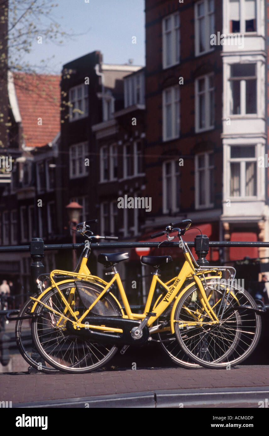 Due di colore giallo brillante biciclette parcheggiate in ponte sul canale di ringhiere, Spiegelgracht, Amsterdam, Paesi Bassi Foto Stock