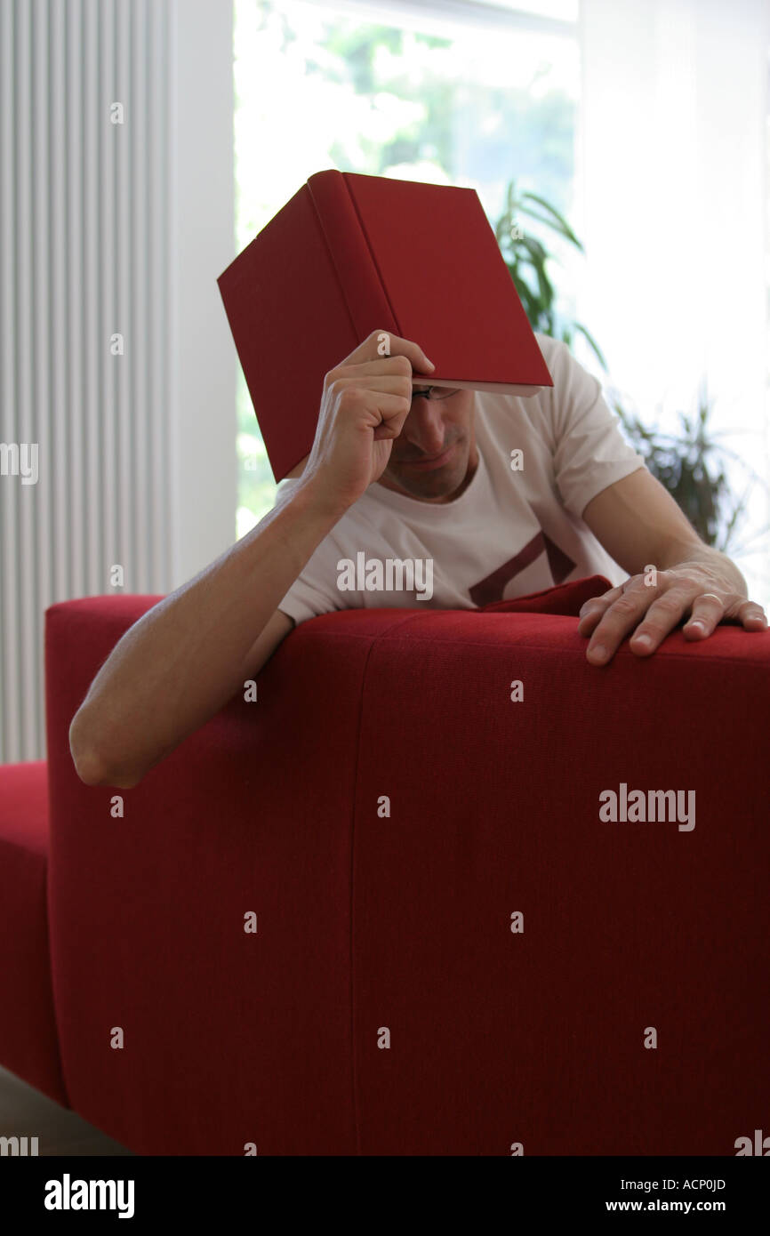 La lettura sul divano - Mann mit Buch Foto Stock