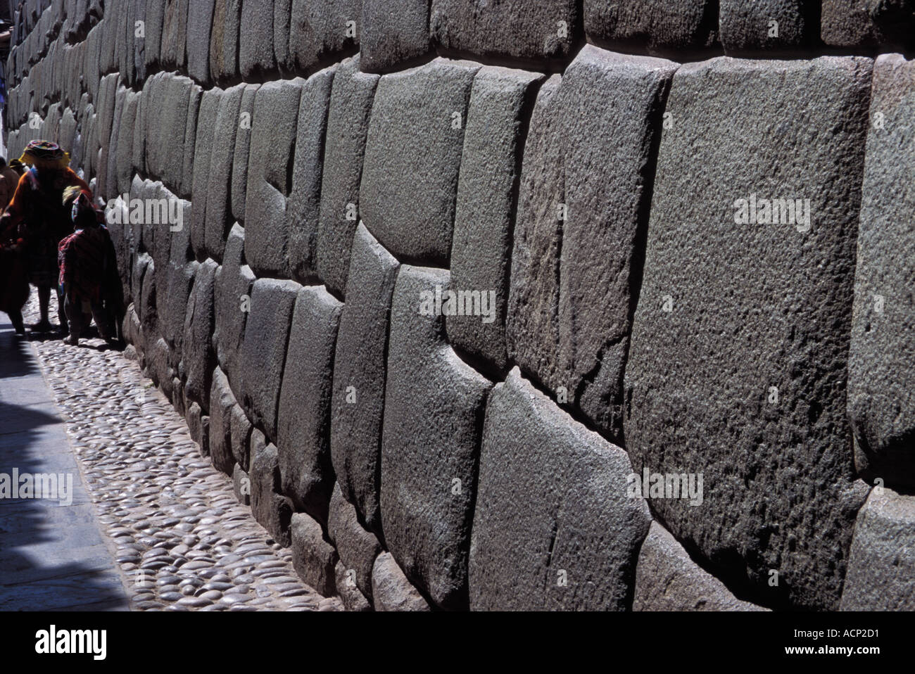 Enti locali indiani a piedi sulla strada di ciottoli con Inca antico muro di pietra Cuzco, Perù Foto Stock