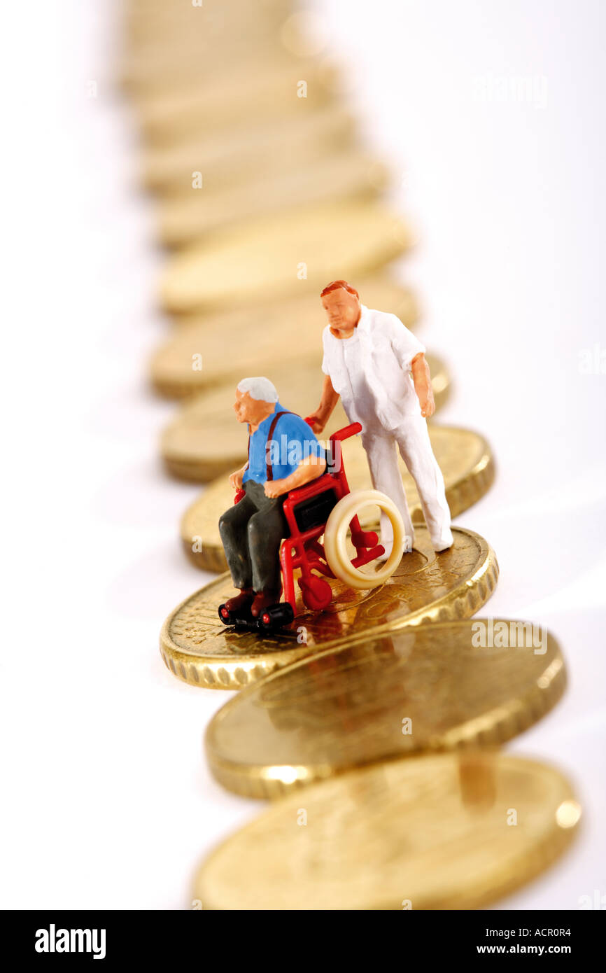Statuetta in sedia a rotelle e il caregiver sulla fila di monete Foto Stock