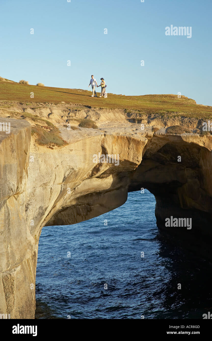 Giovane su Arco Naturale Spiaggia Tunnel Dunedin Isola del Sud della Nuova Zelanda Foto Stock