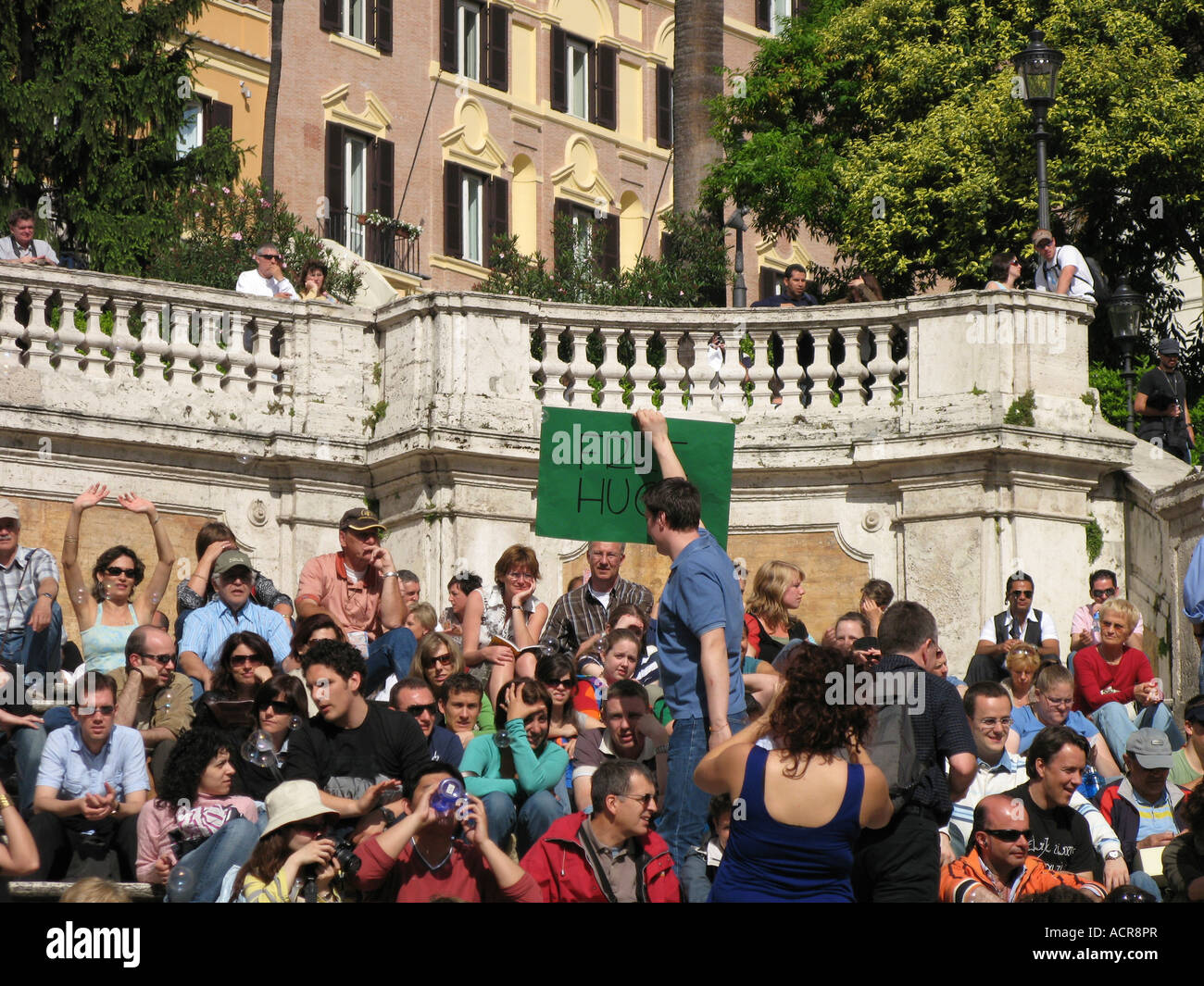 Uomo con segno dando via libera abbracci alla Scalinata di piazza di Spagna Roma Italia Foto Stock