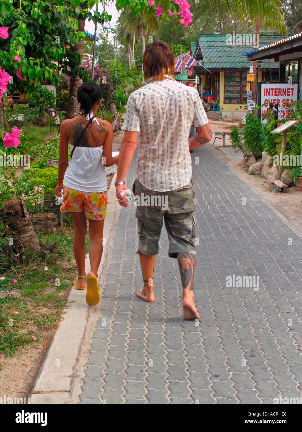 Giovane con tatuaggi passeggiata sul viale lastricato lungo la spiaggia di Hat Sai Ri sull isola di Ko Tao Thailandia Foto Stock