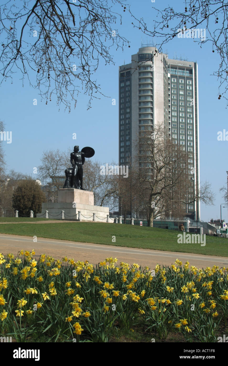 Narcisi degli alberi invernali e statua di Achille in Hyde Park commemorazione Duke of Wellington con l'edificio del grattacielo dell'Hilton Hotel a Park Lane London Regno Unito Foto Stock