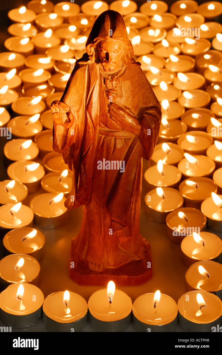 In legno scolpito la Statua di Gesù circondato da bruciare candele votive Foto Stock