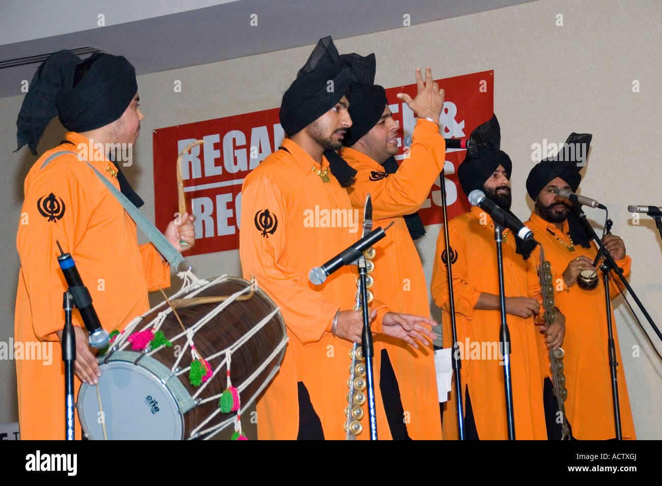 Un gruppo di cantanti in abiti dello zafferano cantando per BHANGRA Foto Stock