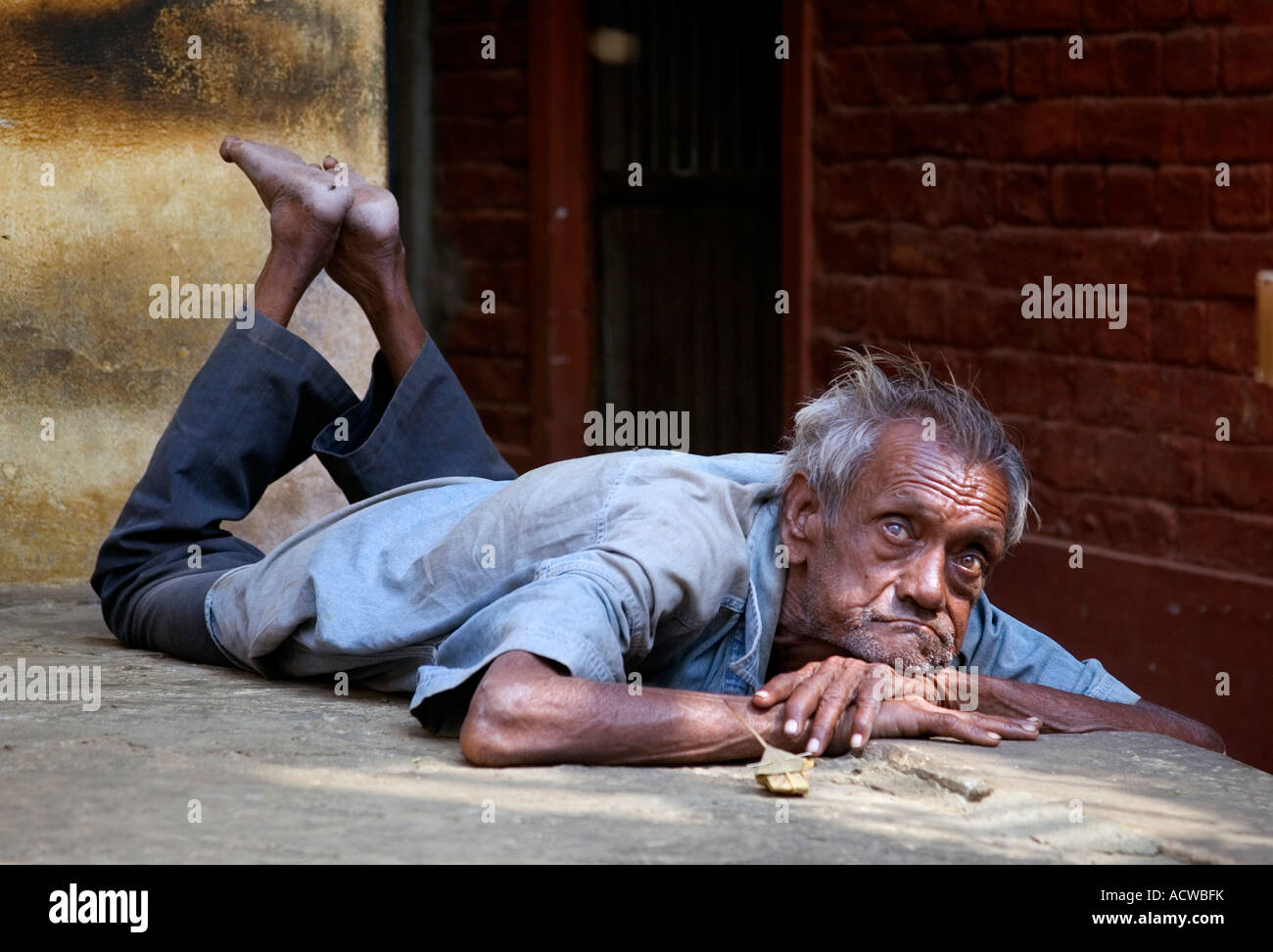 Vecchio pazzo uomo disteso sulla strada Varanasi Benares India Foto Stock