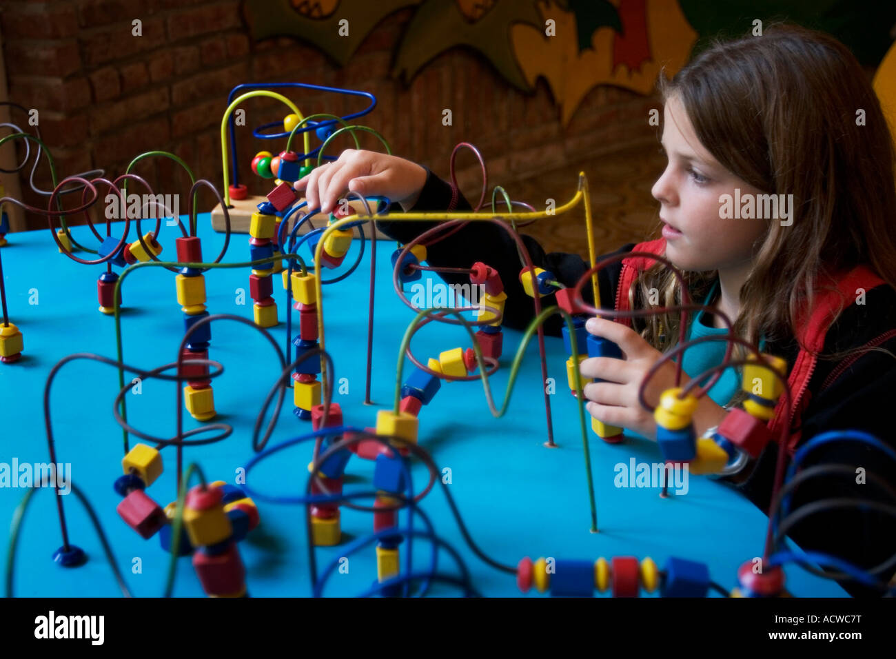 Una bambina gioca con i puzzle in una tabella blu Foto Stock