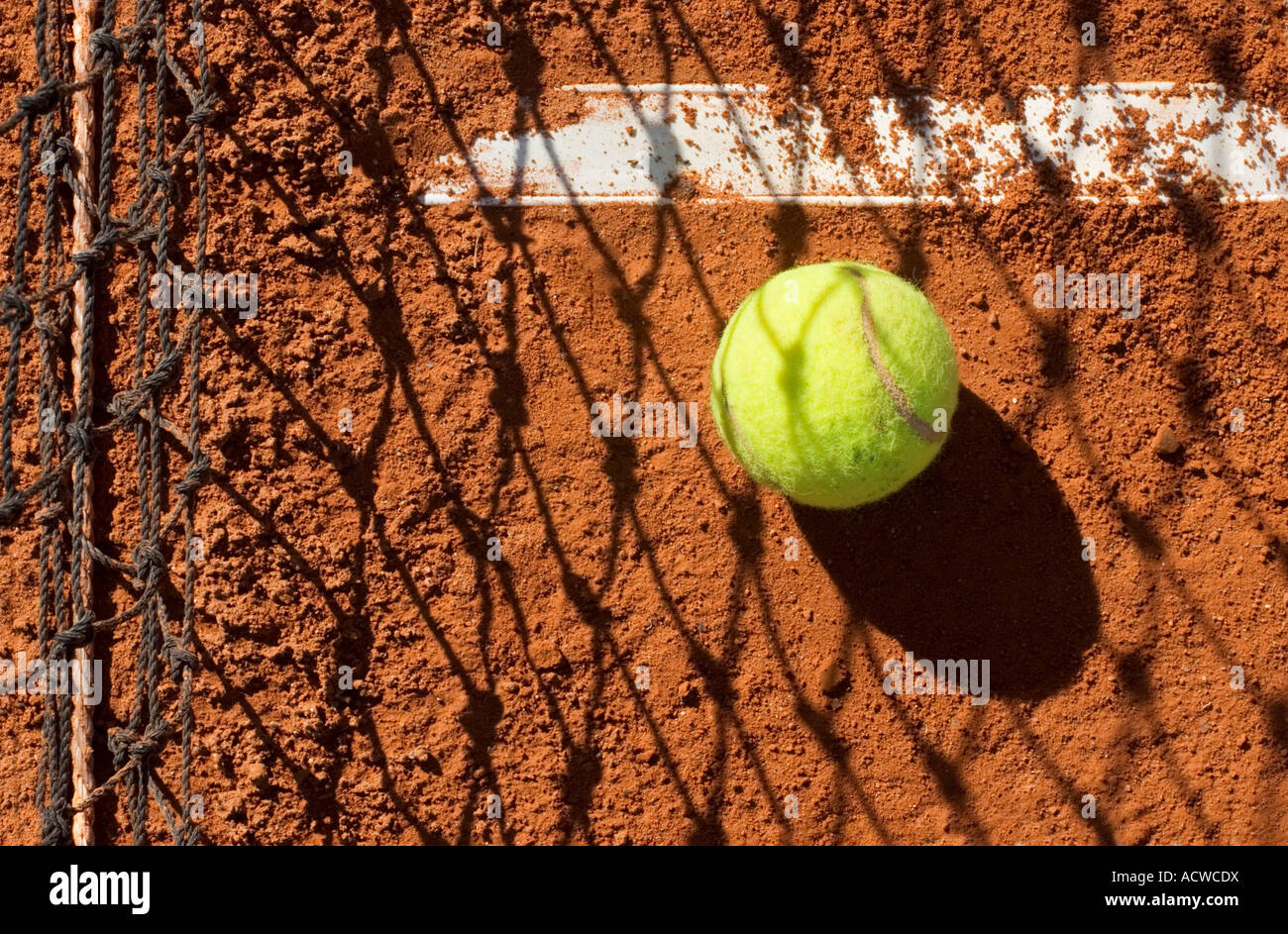 Una palla da tennis con i dettagli di una racchetta , ombre e di una corte di argilla Foto Stock