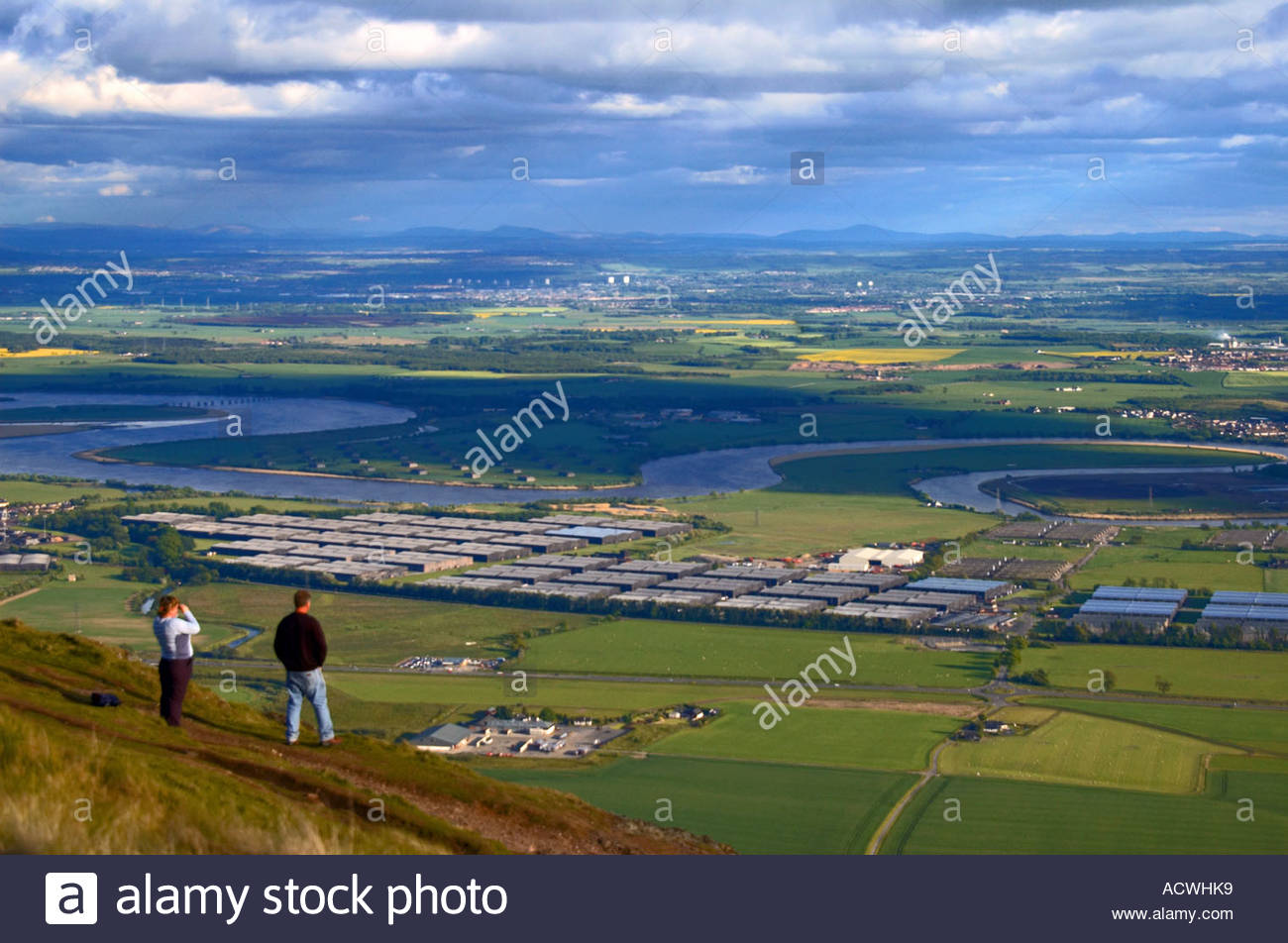 Due escursionisti che si affacciano sulla Forth Valley e sul fiume che si estende dalla cima della collina di Dumyat, Scozia Foto Stock