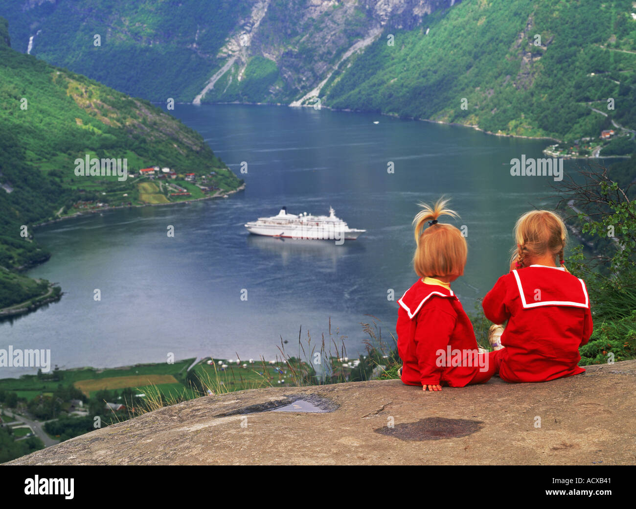 Sorelle in abiti rossi seduto sopra il Geirangerfjord con crociera nave passeggeri nel nord della Norvegia Foto Stock