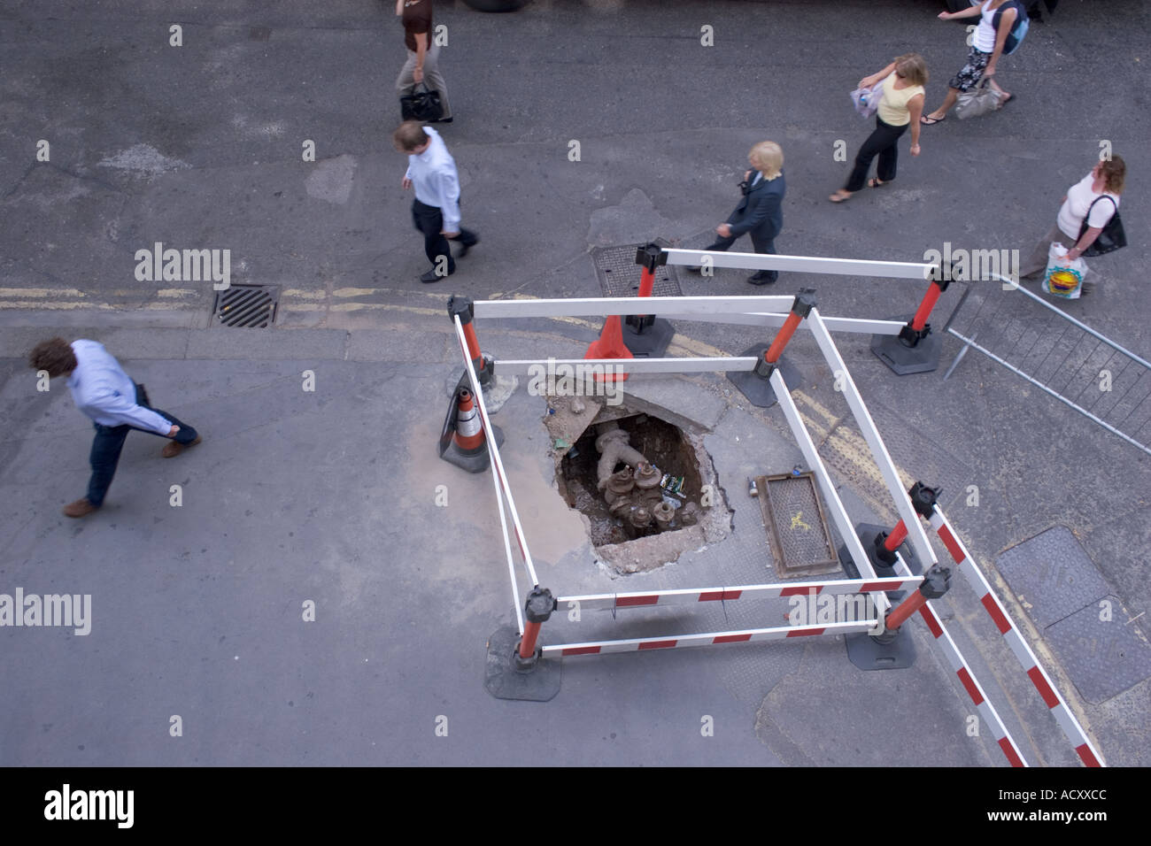 Burst acqua principale con pedoni a piedi intorno cordone barriera e lavori stradali città di Londra Foto Stock