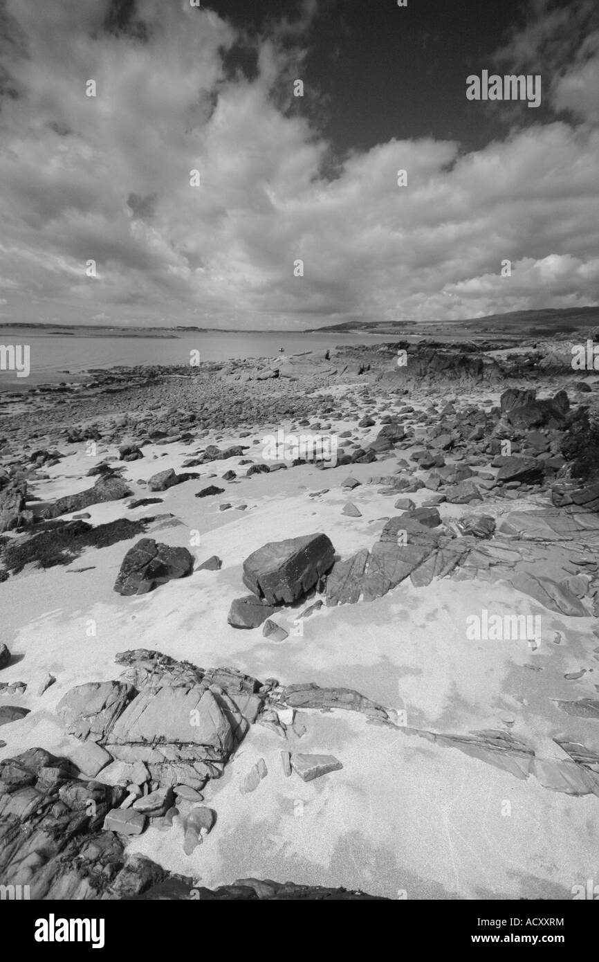 Vista lungo il litorale di Galloway disseminato di massi di scogli e sabbia fine per le lontane colline oltre Foto Stock