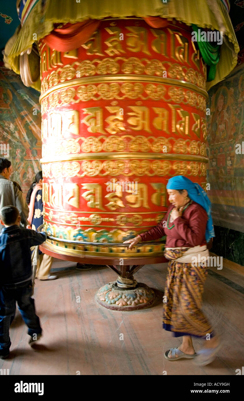 Donna tibetana la filatura di una grande ruota di preghiera.Tsamchen Gompa.Bodhnath Stupa.Valle di Kathmandu.Nepal Foto Stock