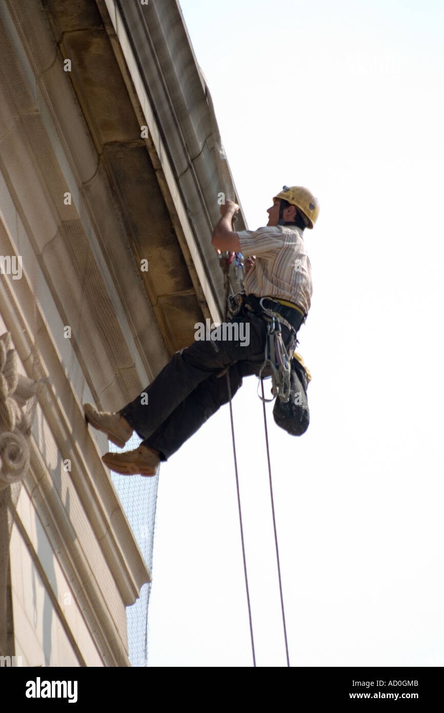 Lavoratore la discesa in corda doppia verso il basso la parte anteriore di Sheffield City Hall per fissare il banner per facciata Foto Stock