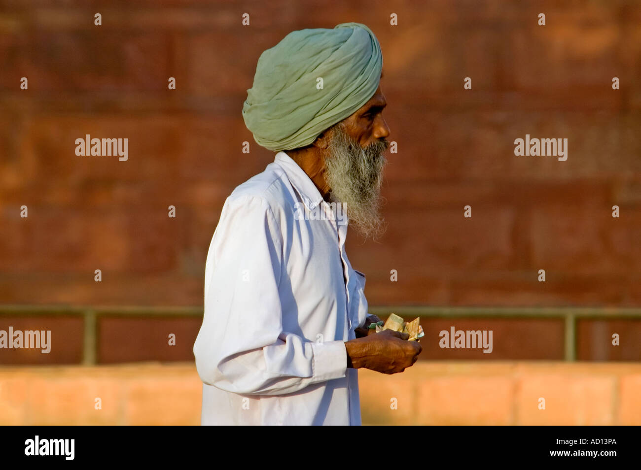 Ritratto orizzontale di un anziano uomo indiano contando il suo rupie all'entrata del Red Fort Foto Stock