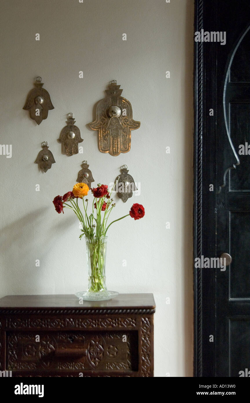 Disposizione semplice di fiori accanto a una raccolta di mani di Fatima (Khamsah) in una camera da letto di Riad Azzar, Marrakech, Marocco. Foto Stock