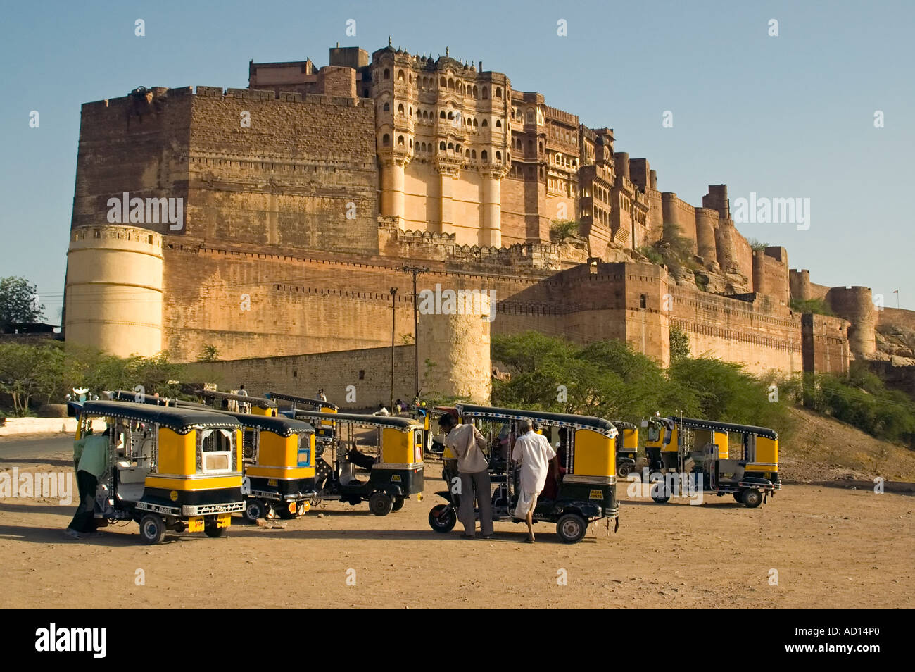 In orizzontale ampia angolazione della parte esterna del Forte Mehrangarh di Jodhpur con auto rickshaws parcheggiato di fronte contro un cielo blu Foto Stock