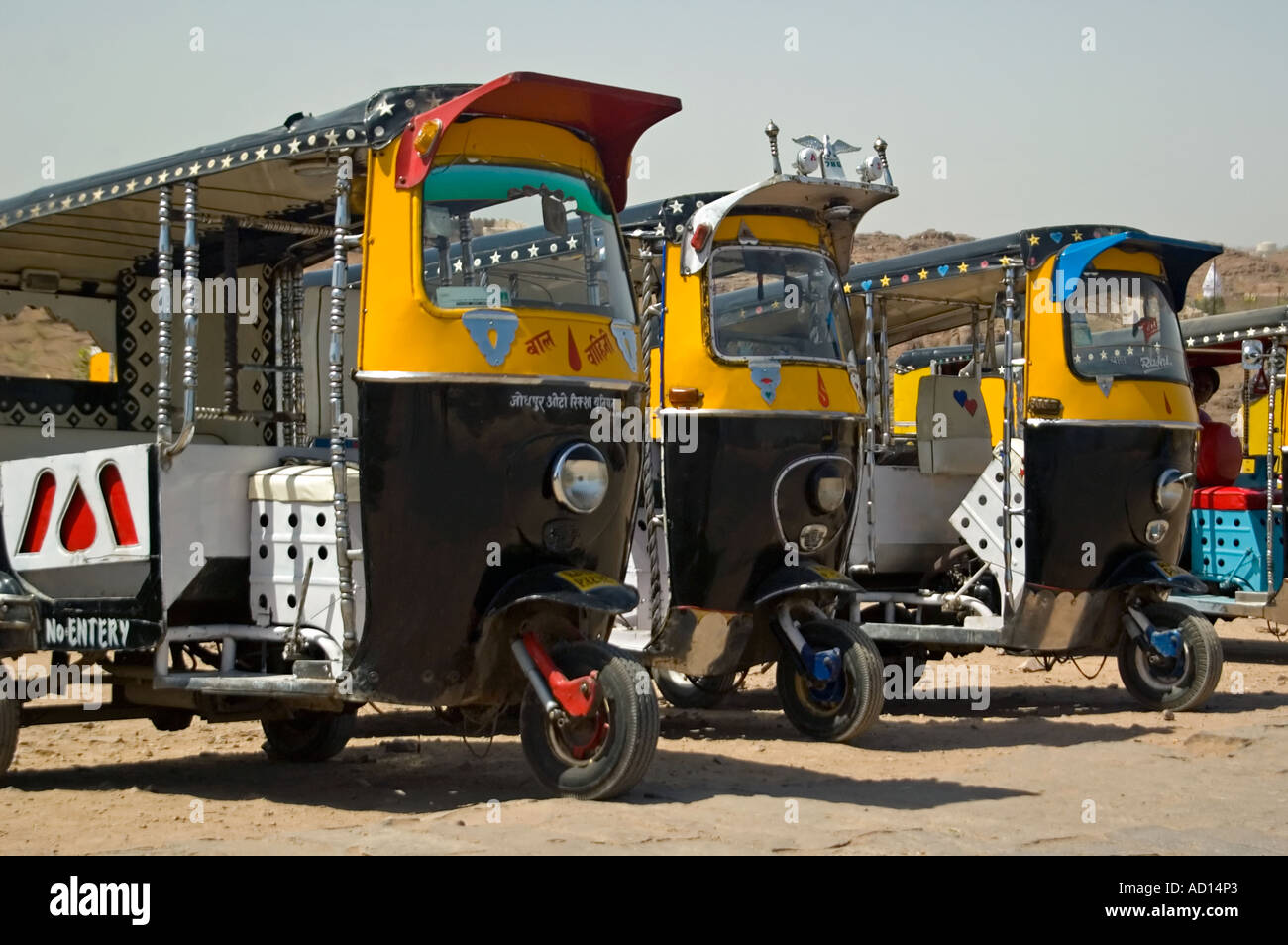 Chiudere orizzontale di una fila di spumante di pulire il giallo e il nero risciò motorizzati parcheggiati fuori di 'Mehrangarth Fort' in Jodhpur Foto Stock