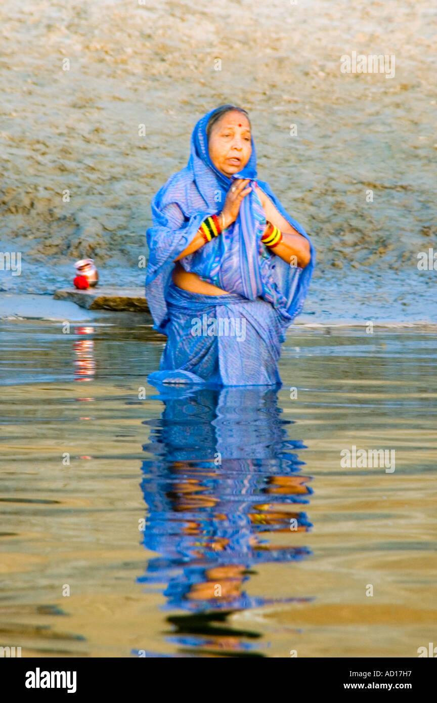 Ritratto verticale di una donna Indiana pregando, semi sommerso nel fiume Gange. Foto Stock