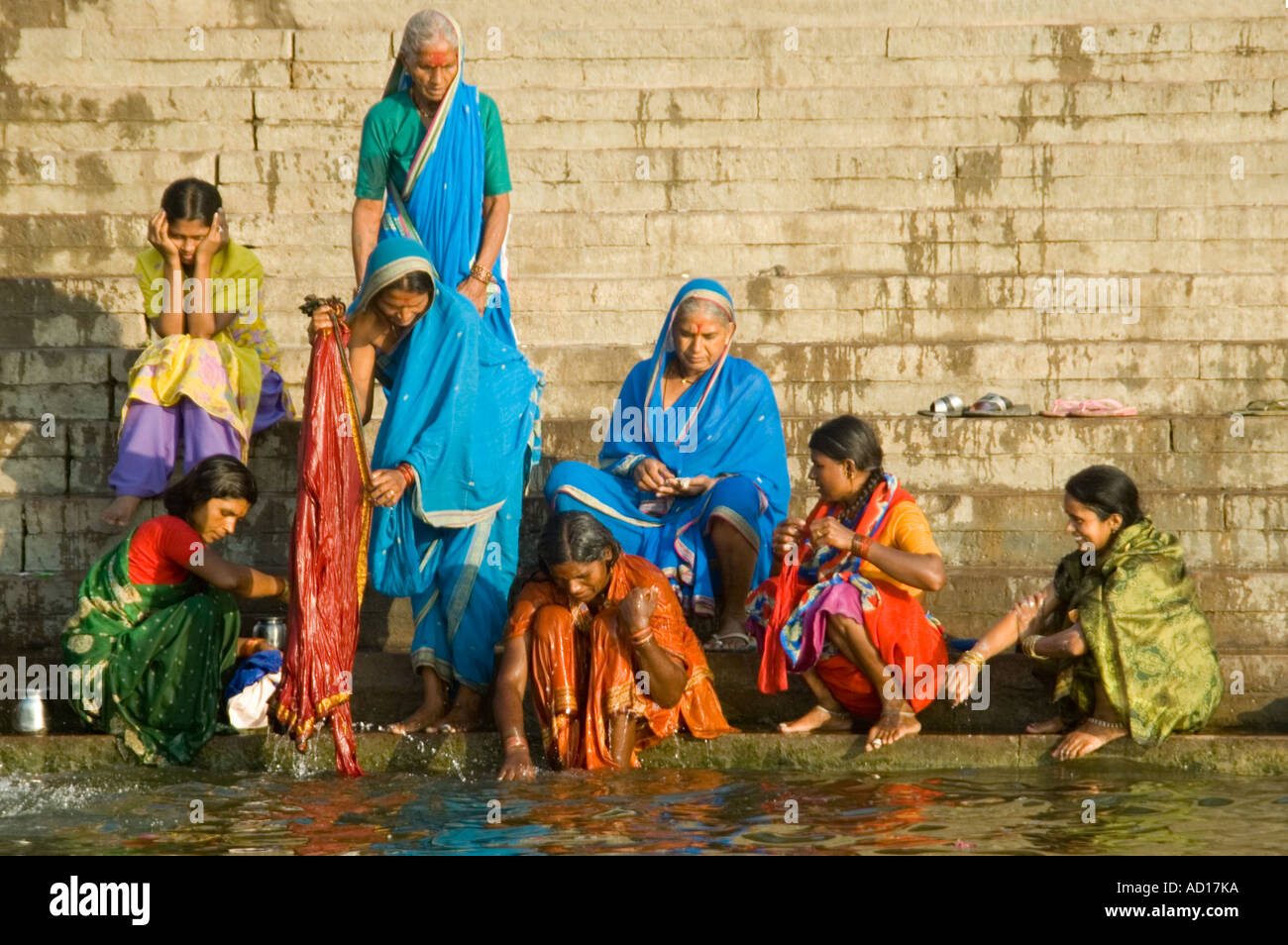Ritratto orizzontale di un gruppo di donne indiane in sari tradizionale di lavaggio in corrispondenza dei ghats lungo il fiume Gange. Foto Stock