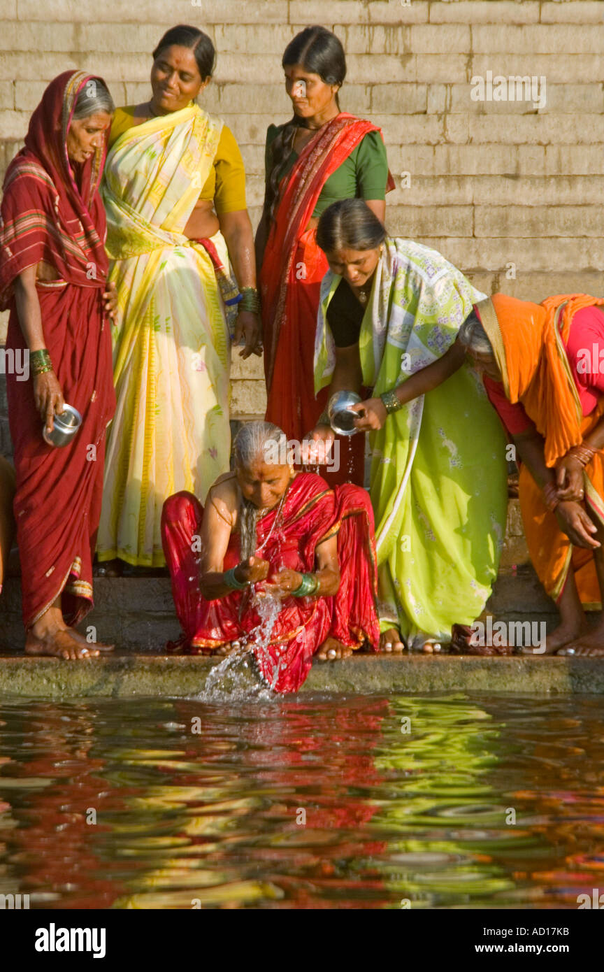 Chiudere verticale su ritratto di un gruppo di donne indiane in sari colorati lavaggio nel fiume Gange. Foto Stock