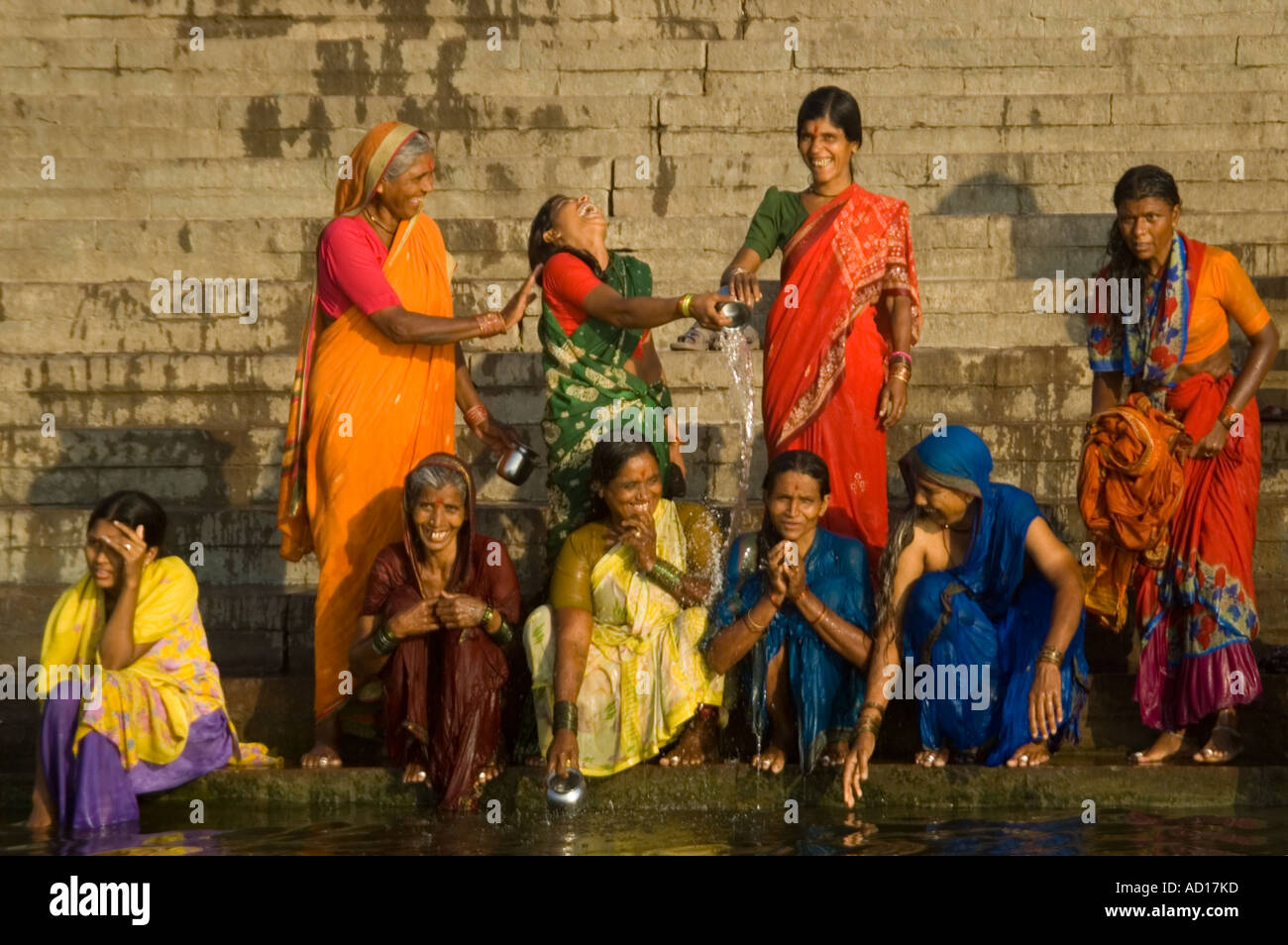 Chiudere orizzontale su ritratto di felice le donne indiane squatting e permanente sulla Ahilyabai Ghat nelle prime ore del mattino di sole. Foto Stock
