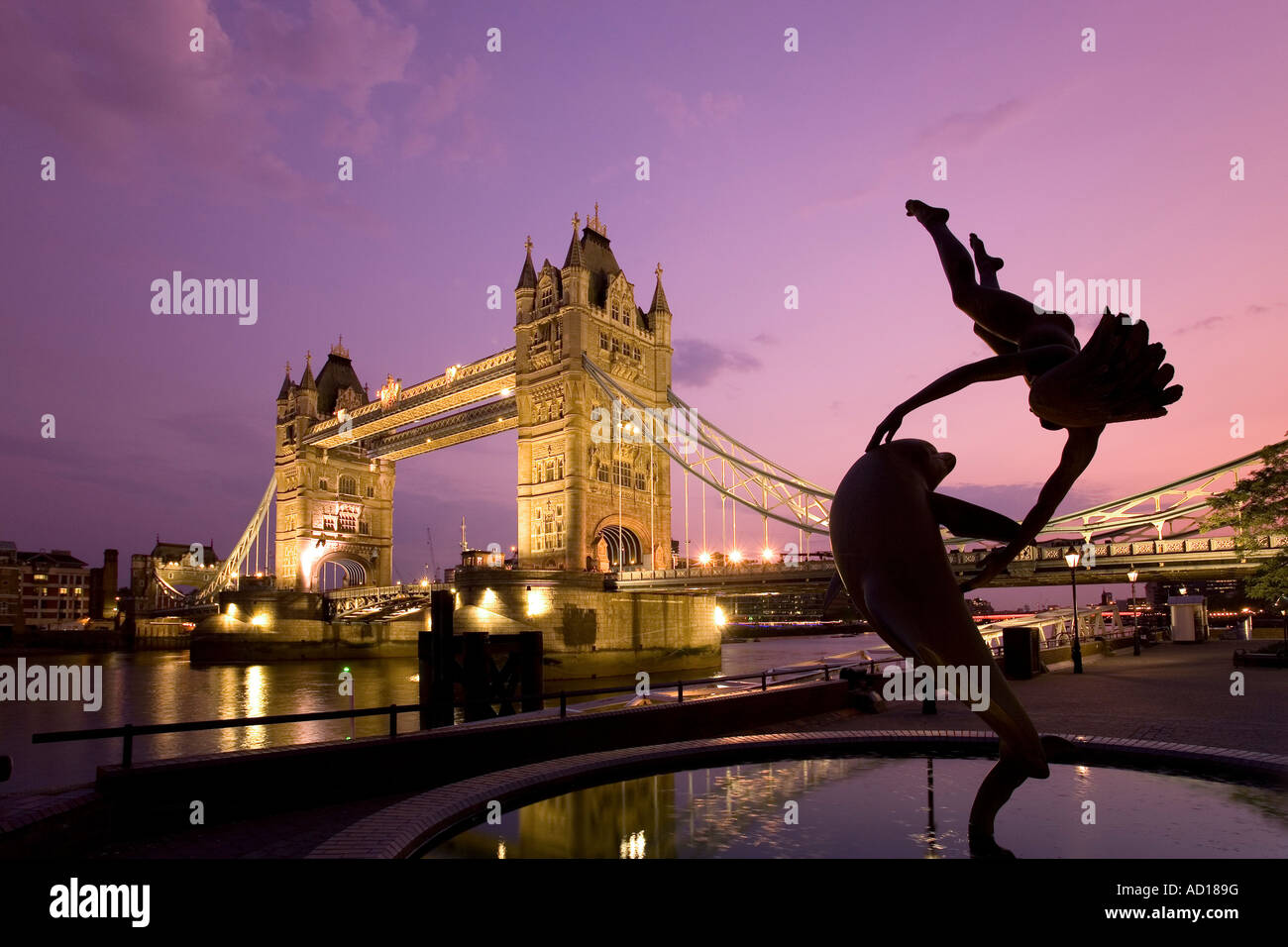 Il Tower Bridge e la "Ragazza con un delfino' Statua fontana al tramonto, Londra, Inghilterra Foto Stock