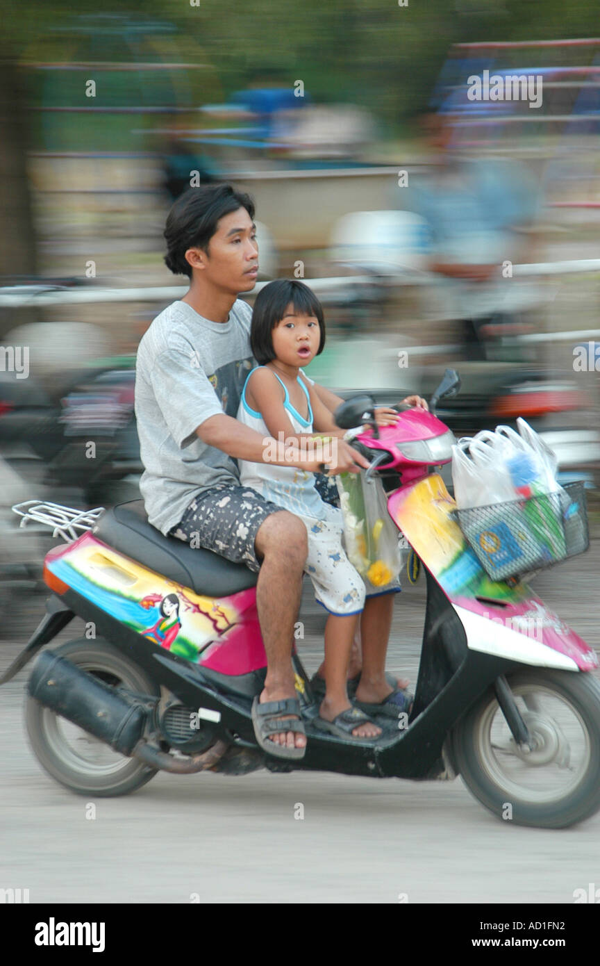 Fratello e Sorella di giovani accelerando su una motocicletta per le vie di Lopburi Thailandia Foto Stock