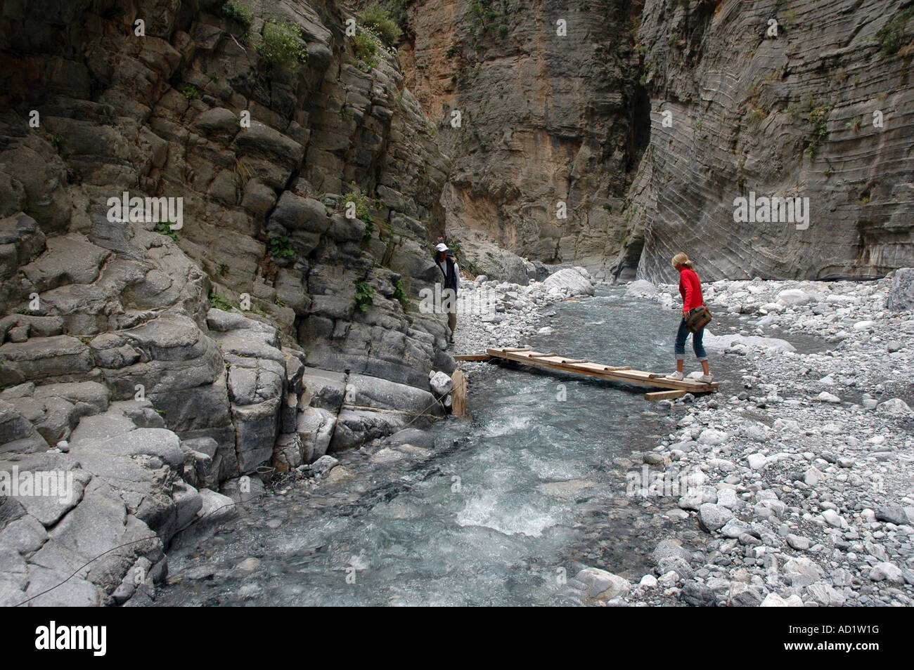 Giovane donna attraversando il ruscello in Samaria Gorge National Park, nell'isola greca di Creta Foto Stock