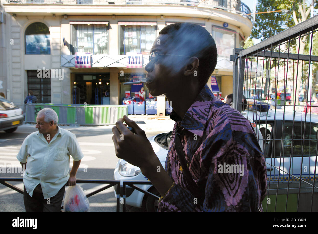 Un uomo soffi su una sigaretta in Barbès Rochechouart distretto di Parigi. Foto Stock